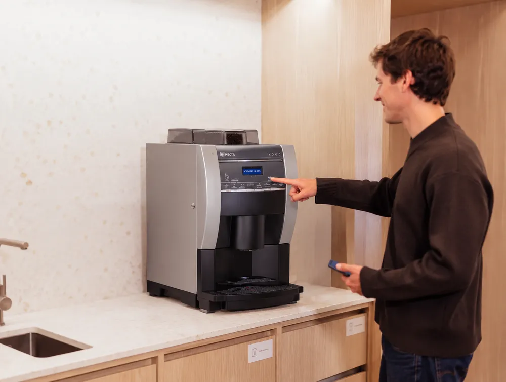 Persona seleccionando un café en una máquina superautomática de oficina